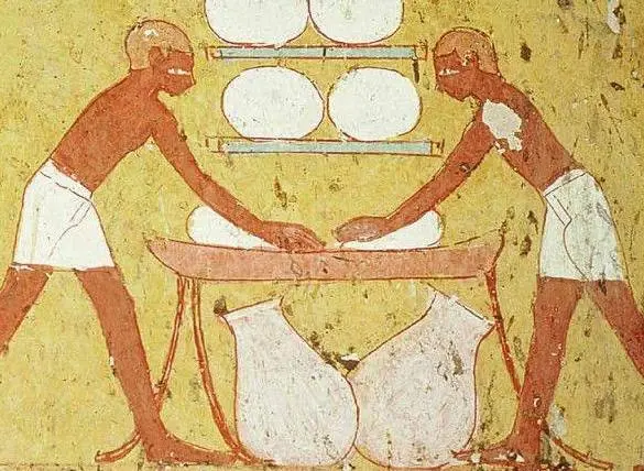 Two ancient Egyptian workers making Egyptian Baladi bread.